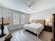 Comfortable bedroom with a ceiling fan, two windows, decorative art, and wooden-look tile flooring at 368 Alcove Dr, Groveland, FL 34736