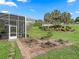 Landscaped backyard with decorative brickwork, lush lawn, and screened lanai, creating a private outdoor space at 39023 Griffin Lndg, Lady Lake, FL 32159
