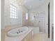 Bright bathroom features a chandelier, an oval soaking tub, and glass shower at 39023 Griffin Lndg, Lady Lake, FL 32159