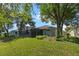 Spacious backyard with lush lawn, mature trees, and screened-in lanai at 4717 Inverness Dr, Leesburg, FL 34748