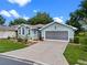 Charming one-story home with beautiful landscaping, lush lawn, and a screened two-car garage on a sunny day at 4717 Inverness Dr, Leesburg, FL 34748
