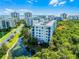 Low-angle aerial view of a condo building with blue exterior balconies, landscaping, and a pond at 5300 S Atlantic Ave # 16-202, New Smyrna Beach, FL 32169
