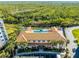Aerial view of a pool, palm trees, and parking at the rec building, backed by a marsh landscape at 5300 S Atlantic Ave # 16-202, New Smyrna Beach, FL 32169