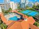 Aerial view of a pool and sunbathing area, tennis courts, and palm trees at the condo complex at 5300 S Atlantic Ave # 16-202, New Smyrna Beach, FL 32169
