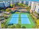 Aerial shot of tennis courts, a pool, and rec building at the condo community, surrounded by palms at 5300 S Atlantic Ave # 16-202, New Smyrna Beach, FL 32169