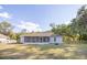 Expansive backyard with a screened porch, mature trees, green grass, and a charming fire pit area at 548 E Belt Ave, Bushnell, FL 33513