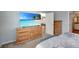 Comfortable bedroom featuring neutral walls, wood furniture, and view into a recreation room at 5702 Grimes Ct, The Villages, FL 32163
