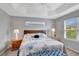 Comfortable bedroom featuring a tray ceiling, two windows, and a bed with floral pattern bedding at 5702 Grimes Ct, The Villages, FL 32163
