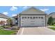 Exterior view of the single Gathering home showing two-car garage with decorative carriage hardware at 5702 Grimes Ct, The Villages, FL 32163