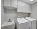 Bright laundry room featuring white cabinets, a utility sink, and modern washer and dryer appliances at 5702 Grimes Ct, The Villages, FL 32163