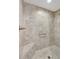 Tiled walk-in shower featuring a bench, rainfall shower head, grab bar, and neutral tiling at 5702 Grimes Ct, The Villages, FL 32163