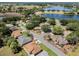 Expansive aerial view of homes nestled among mature trees, with a lake in the background, offering tranquil community living at 5906 Prince Philip Ct, Leesburg, FL 34748