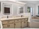 Bright bathroom features double sinks, lighted mirrors, and stylish vanity with black hardware at 5906 Prince Philip Ct, Leesburg, FL 34748