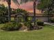 Charming one-story home with well-manicured lawn and lush landscaping featuring palm trees and decorative rock garden at 5906 Prince Philip Ct, Leesburg, FL 34748