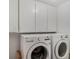 Bright laundry room featuring a white LG washer and dryer set, plus white cabinetry above at 5906 Prince Philip Ct, Leesburg, FL 34748