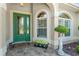 Close-up of a home's green front door with decorative glass and an arched window, with a stone walkway at 630 Laurel Run, The Villages, FL 32162