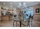 Elegant dining area with a glass-top table, modern chandelier, and seamless connection to the kitchen and living room at 725 Beldon Ct, The Villages, FL 32162