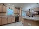 Kitchen features wood cabinets, a black dishwasher, tile flooring, and neutral countertops, perfect for cooking and cleaning at 725 Beldon Ct, The Villages, FL 32162