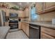 Kitchen with light wood cabinets, stainless steel appliances and view from sink to microwave and stove at 725 Beldon Ct, The Villages, FL 32162
