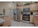 Spacious kitchen with stainless steel appliances including a refrigerator, oven, microwave, and wood cabinets at 725 Beldon Ct, The Villages, FL 32162