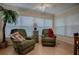 Cozy living room with two recliners, faux tree, small cabinet, and a bright window with blinds at 725 Beldon Ct, The Villages, FL 32162