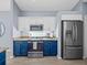 Modern kitchen with stainless steel appliances, granite countertops, and bright blue and white cabinetry at 9027 Saint Andrews Way, Mount Dora, FL 32757