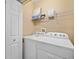 Laundry room featuring a white washer and dryer with storage shelves at 9027 Saint Andrews Way, Mount Dora, FL 32757