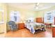 Bright, airy bedroom with a ceiling fan, two windows, and a comfortable bed with wicker chair at 915 Sutherland Ct, Leesburg, FL 34788
