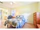 Cozy bedroom featuring natural light, ceiling fan, comfortable bedding, and a view into a bathroom at 915 Sutherland Ct, Leesburg, FL 34788
