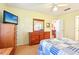 Bedroom with hardwood floors, dresser, ceiling fan, comfortable bedding, and a bright, inviting space at 915 Sutherland Ct, Leesburg, FL 34788