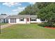 Charming single-story home with a well-manicured lawn, red door, and mature trees at 915 Sutherland Ct, Leesburg, FL 34788