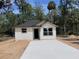 Newly constructed one-story home with a concrete driveway and neutral siding, set amongst mature trees at Lot 43 Indian Estates Cr 423, Lake Panasoffkee, FL 33538