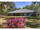 Lush backyard view featuring mature trees, colorful flowers, and a charming patio at 10159 Se 174Th St, Summerfield, FL 34491