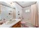 Well-lit bathroom with a classic vanity, decorative wallpaper, and shower-tub combination at 10159 Se 174Th St, Summerfield, FL 34491