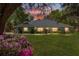 Scenic view of a single story home at dusk, complete with a lush lawn and flowering bushes at 10159 Se 174Th St, Summerfield, FL 34491