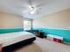 Comfortable bedroom featuring neutral walls accented by a vibrant turquoise trim, a ceiling fan, and plush carpeting at 10323 Joanies Run, Leesburg, FL 34788