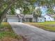 Charming single-story home with a long driveway, well-manicured lawn, a palm tree, and an attached garage at 10323 Joanies Run, Leesburg, FL 34788