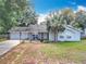 Charming single-story home with a well-manicured lawn, a palm tree, and an attached garage with a basketball hoop at 10323 Joanies Run, Leesburg, FL 34788