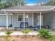 Covered front porch featuring a bench, landscaping, and a clear view of the house number at 10323 Joanies Run, Leesburg, FL 34788
