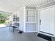 Close-up of the covered front porch with a bench, decorative plants, and a view of the front door at 10323 Joanies Run, Leesburg, FL 34788