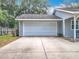 A spacious two-car garage with a concrete driveway, complemented by the home's charming exterior at 10323 Joanies Run, Leesburg, FL 34788