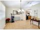 A spacious living room with neutral walls and tile flooring, complemented by a modern chandelier and a peek into the kitchen at 10323 Joanies Run, Leesburg, FL 34788