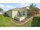 Backyard featuring a small patio area, a grill, and a lush yard with beautiful landscaping and mature trees at 1061 Woodruff St, The Villages, FL 32162