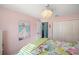 Comfortable bedroom featuring tropical bedding, light pink walls, and an open doorway to the next room at 1061 Woodruff St, The Villages, FL 32162