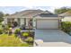 Charming single-story home with a well-manicured lawn and a two-car garage with a retractable screen at 1061 Woodruff St, The Villages, FL 32162