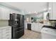 Open-concept kitchen featuring stainless steel appliances, white cabinetry, and an eat-in counter at 1061 Woodruff St, The Villages, FL 32162