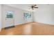 Bright living room with wood floors, white walls, a ceiling fan, and natural light from a large window at 1109 Hampton St, Clermont, FL 34711