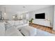 Bright living room featuring a large white sectional couch, wood floors, and a modern entertainment center at 113 Camilla Rd, Deland, FL 32724