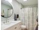 This bathroom has a sleek vanity, round mirror, and patterned shower curtain at 1208 Santa Cruz Dr, The Villages, FL 32162