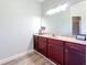 Bathroom with a large mirror above a vanity with wood cabinets and a marble countertop at 13013 County Road 561A, Clermont, FL 34715